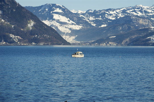 Boot mit Angelruten auf dem See mit Schneebergen