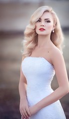 Fototapeta na wymiar Beautiful bride blonde with stylish make-up in white dress