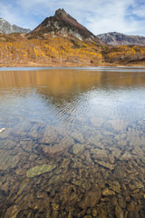 Lake. Water reflects mountain. Autumn forest. Clear water