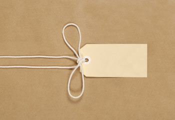 Brown paper package parcel background tied with string or rope and blank message tag or address...