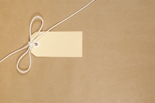 Brown paper package parcel background tied with string or rope and blank message tag or address label photo 