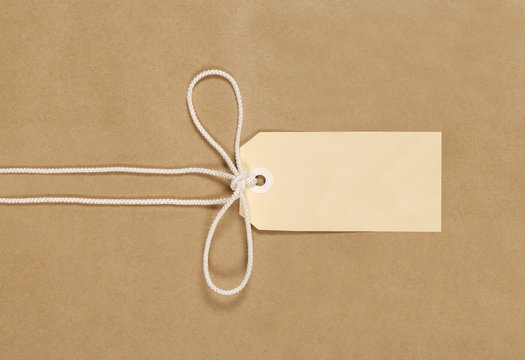 Brown paper package parcel background tied with string or rope and blank message tag or address label photo