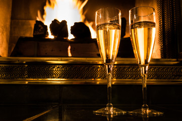 Two glasses of champagne in front of a romantic fire