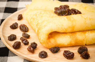 Pancake with raisin on wooden plate
