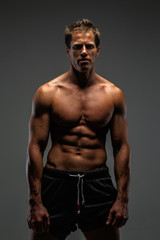 Fototapeta premium Male with naked torso in sports shorts isolated on grey