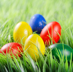 Colorful Easter eggs lying in a pyramid shape on green grass in