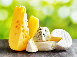 Different types of cheese on a black wooden table and on nature