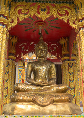 the gold buddha statue sitting under the sun light