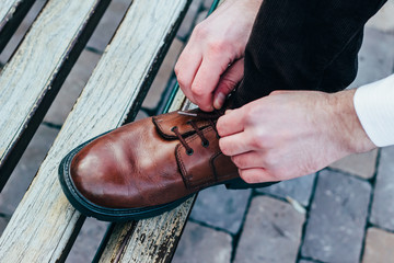 Man tying the laces on the brown boots.