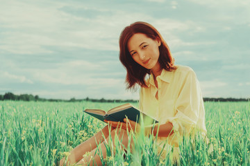 Naklejka na ściany i meble Woman sitting on summer meadow with a book