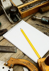 Paper with pencil and the vintage working tools on wooden