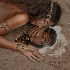 Beautiful girl in ethnic jewelry with mirror covered with sand