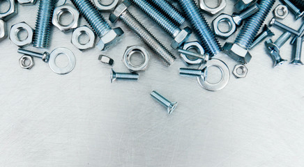 Nuts, screws and bolts on scratched metal background.