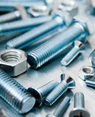 Nuts, screws and bolts on scratched metal background.