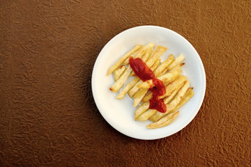 french fried topped with tomato sauce on brown background