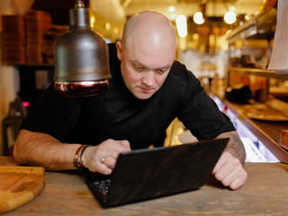 Bald young man looking at laptop