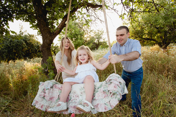 Fototapeta premium Родители катают дочь на качеле