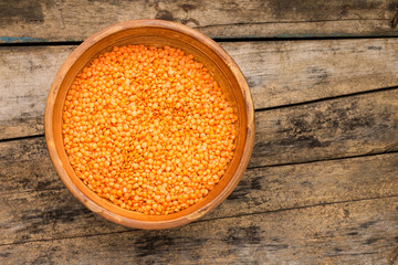 Raw lentil in bowl on wooden background