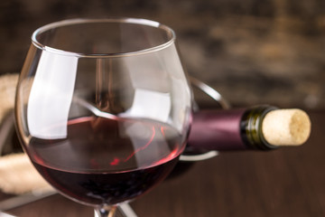 Red wine in wineglass against corked bottle