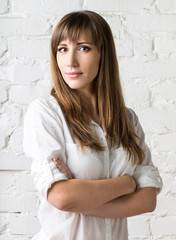 Obraz premium Young pretty woman standing against white brick wall.