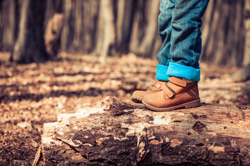 child in boots at old spring forest tree