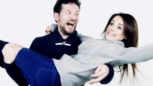 Man holding girlfriend in arms making her turn around happy