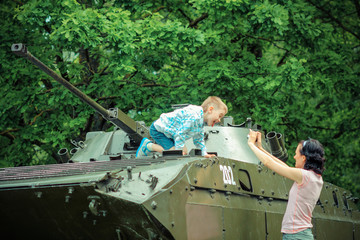 Mom takes pictures of  son on vintage military vehicle.