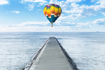 Old pathway into the sea with hot air balloon over