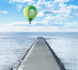 Old pathway into the sea with hot air balloon over