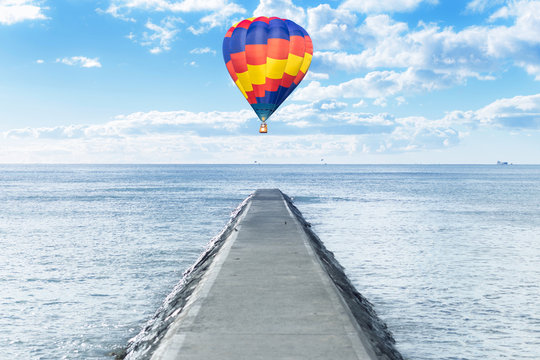 Old pathway into the sea with hot air balloon over
