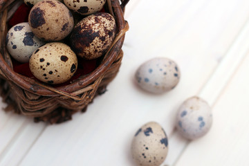 Quail eggs in a wicker basket on a wooden background