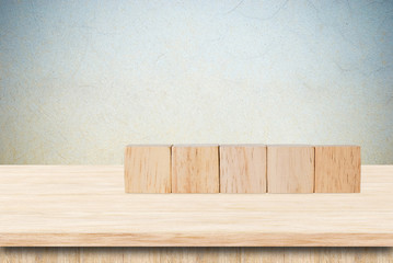 Five wooden cubes on table over grunge cement wall