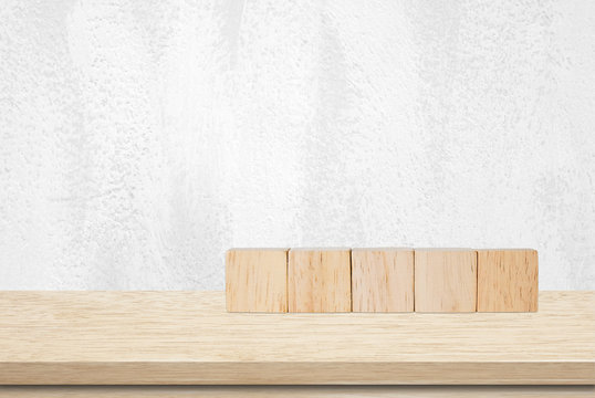 Five wooden cubes on table over white wall