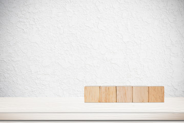 Five wooden cubes on table over white cement wall background