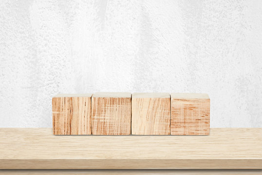 Four wooden cubes on table over white cement wall