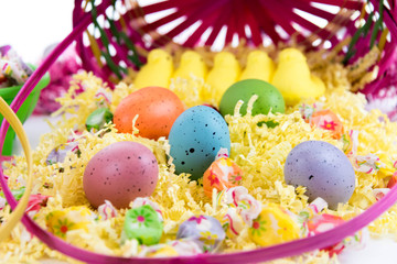 colored Easter eggs, yellow chicks and candy in a basket