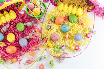 Fototapeta na wymiar colored Easter eggs, yellow chicks and candy in a basket