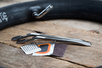 Bicycle repair kit  with tube in background on wooden table