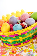 colored Easter eggs, yellow chicks and candy in a basket