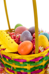 colored Easter eggs, yellow chicks and candy in a basket