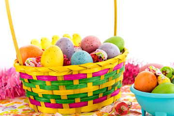 colored Easter eggs, yellow chicks and candy in a basket