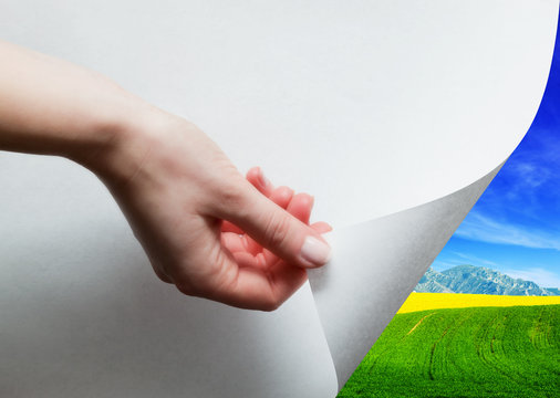 Hand Pulling A Paper Corner To Uncover, Reveal Green Landscape