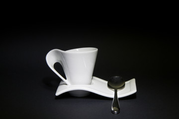 Tazzina da caffè con cucchiaino in acciaio e sfondo nero