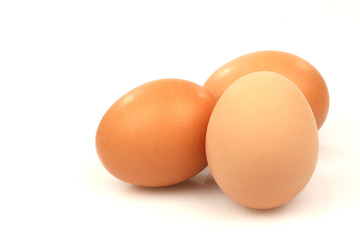 three brown eggs on a white background