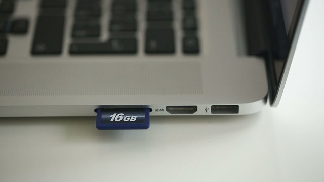 Hand inserting SD card 16Gb in memory card reader of notebook