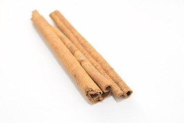 Cinnamon sticks stacked on white background.