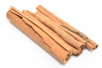Cinnamon sticks stacked on white background.