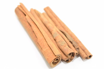 Cinnamon sticks stacked on white background.