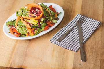 Salat auf kleinem Teller mit Messer und Gabel