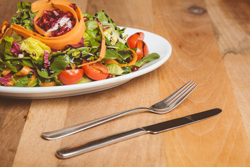 Salat auf kleinem Teller mit Messer und Gabel